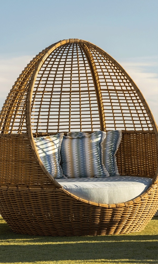 Woven egg daybed with striped pillows in late golden light